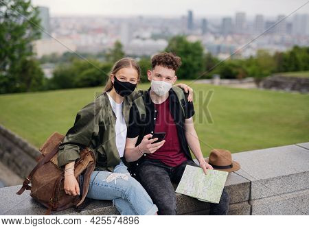 Young Couple Travelers With Map Looking At Camera In City On Holiday, Coronavirus Concept.