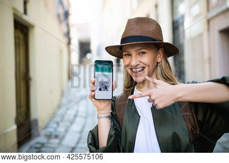 Young Woman Traveler In City On Holiday Showing Covid-19 Vaccine Passport On Smartphone.