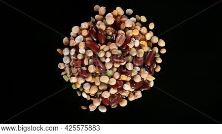 Rotating Raw Various Legumes on Black Background. Top Shot.