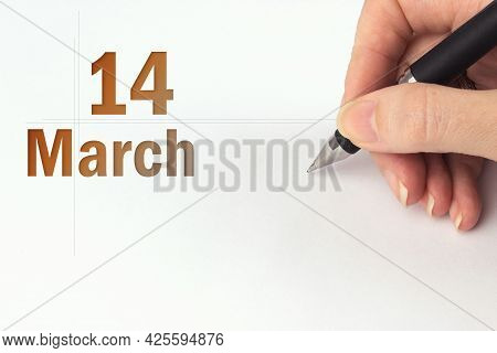 March 14th. Day 14 Of Month, Calendar Date. The Hand Holds A Black Pen And Writes The Calendar Date.