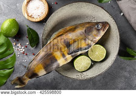 Raw Fish Sea Bass Or Lingcod And Seasonings For Cooking It On A Gray Background Top View Close Up