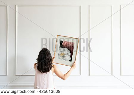 Curator hanging floral art frame on the wall
