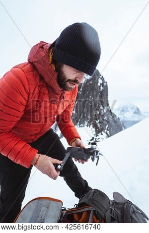 Backpacker setting up a drone in the snowy Segla mountain, Norway