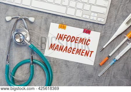 Paper With Infodemic Management On The Office Desk, Stethoscope And Keyboard, Top View