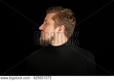 Cute Bearded Man, Half-face Portrait, Black Background. Young Guy In Black Polo Neck Sweater. Confid
