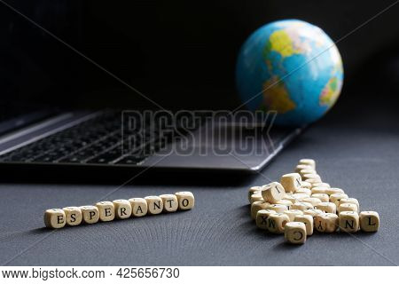 Esperanto Inscription Next To An Open Laptop And A Globe. The Concept Of Studying The Artificial Glo