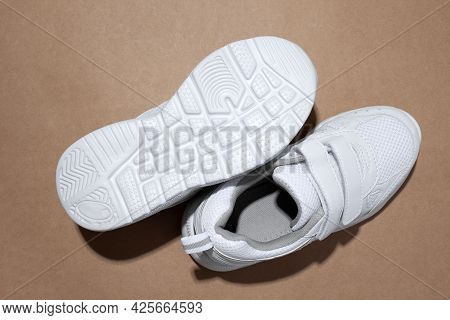Macro Top View Two White Woman Sneakers, One Sneaker Lies Sole Up With Hard Shadows Isolated On A Pa