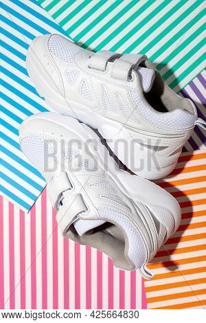 Vertical Top View Two White Kid Sneakers With Velcro Fasteners For Comfortable Footwear On An Abstra