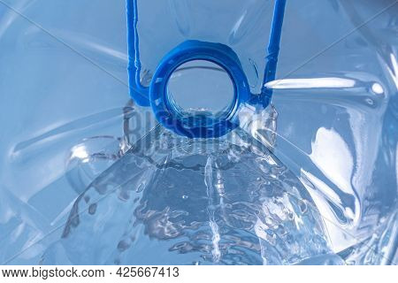 View Inside The Bottle Pouring Fresh Clean Water From A Bottle With Drops Into A Glass On The Table.