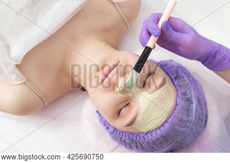 In The Beauty Salon, The Beautician Puts A Mask Of Green Clay On The Face Of A Young Girl. Daily Fac