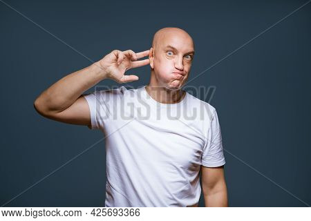 Comic Bald-headed Male Posing On A Blue Background With Emotional Facial Expressions And Raised Hand