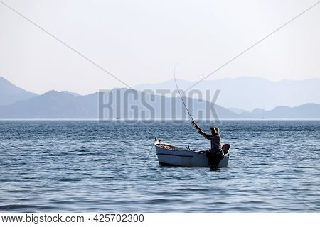 Hisaronu, Turkey - July 2021: Fishing Boat In The Sea On Background Of Mountains In Mist. Fisherman 
