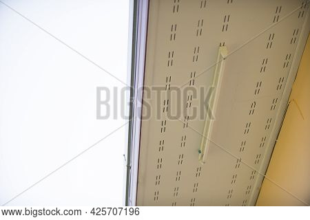 Low Angle View Of Roof Eaves And Neon Soffit At The Ceiling With Sky Background