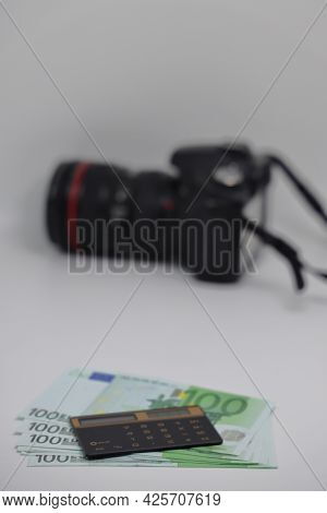 The Calculator Lies On One Hundred Euro Banknotes Against The Background Of A Camera, Earnings On Ph