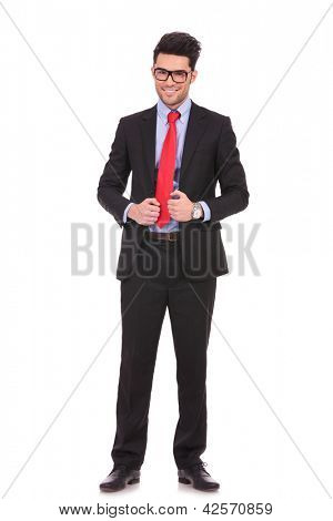 full length picture of a young business man holding his suit jacket with both hands and smiling to the camera on white background