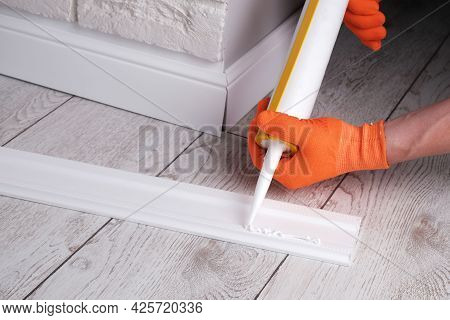 Master Applies Glue To  Skirting Board With  Glue Gun, Hands Close-up
