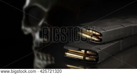 Human Skull In The Background With Loaded 30-fourn Magazines For An Assault Rifle On A Black Backgro