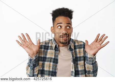 I Know Nothing. Funny African American Man Raising Empty Hands Up And Looking Away, Avoiding Eye Con
