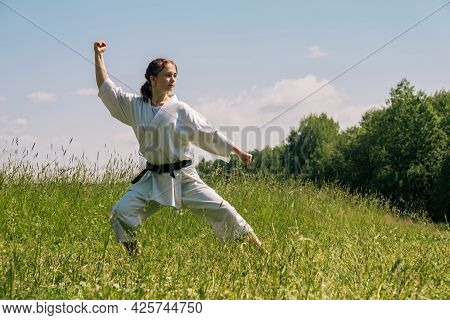 Teen Girl Performing Karate Kata Outdoors In Kokutsu-dachi Stance