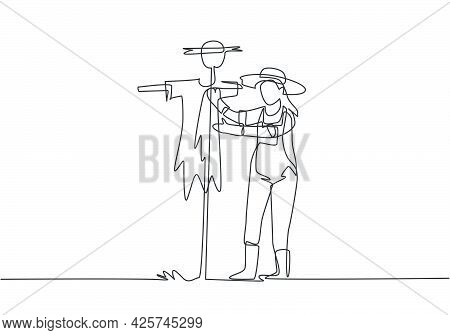 Single Continuous Line Drawing A Young Female Farmer In A Straw Hat Putting Up Scarecrow To Keep Out