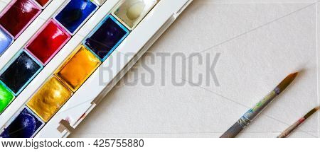Watercolors In Cuvettes In A Box And Brushes For Painting On A White Sheet Of Paper.