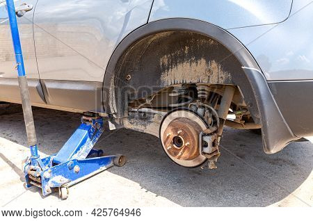 Сar At The Tire Mounting With Removed Wheel On Pneumatic Jack. Seasonal Tire Change. Car Service Con