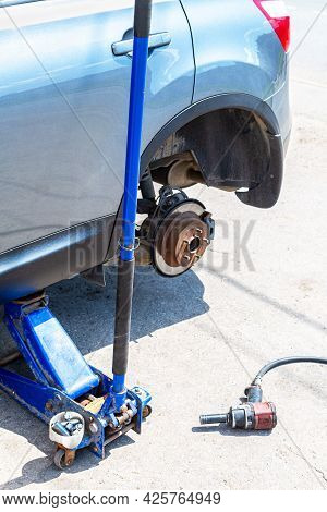 Car At The Tire Mounting With Removed Wheel On Pneumatic Jack. Seasonal Tire Change. Car Service Con