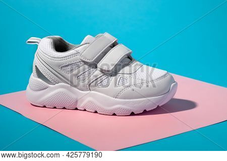 Macro Side View Of One White Unisex Sneaker With Velcro Fasteners For Easy Shoeing On A Geometric Sq