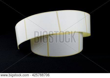Babina Of Self-adhesive Stickers On A Black Background. Self-adhesive White Label Roller For Printin