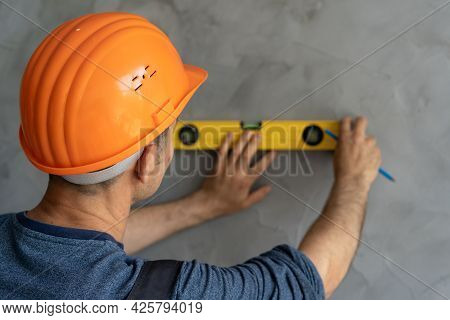 Close-up Architect Or Construction Worker In Hardhat Checking Level Of The Wall With The Level Tool.