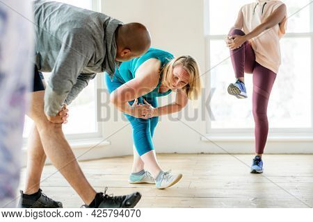 Group of people doing quadriceps stretching in class