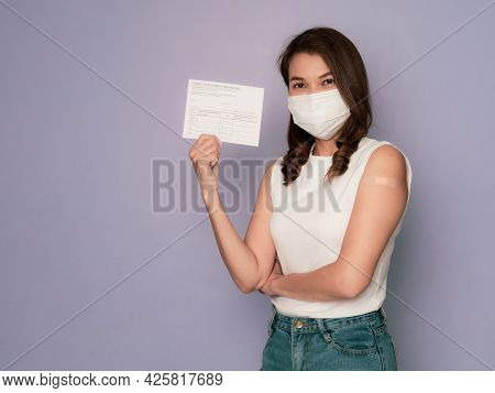 Woman Wearing Medical Protective Hygiene Mask With Band-aid Plaster On Arm Holds And Showing Vaccina