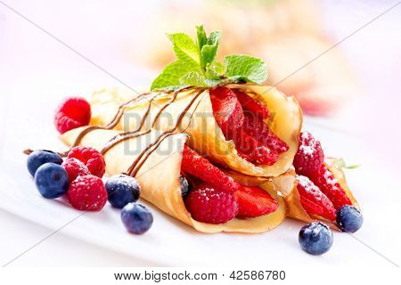 딸기와 크레페입니다. 딸기, 라즈베리, 블루베리, 초콜릿 토 핑과 크 레이프