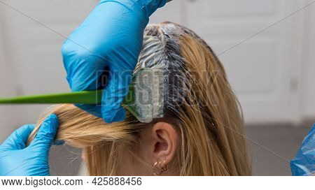 A Hairdresser Applies Paint With A Brush To A Woman's Hair In A Beauty Salon.