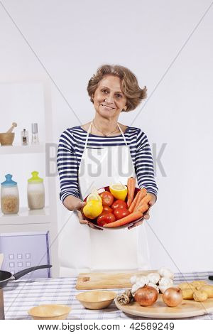 Vacker och glad äldre kvinna matlagning på hennes kök