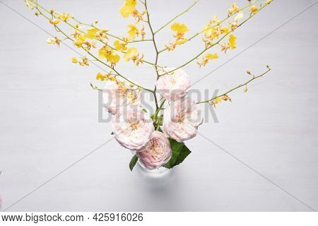 Orchid Oncidium Flower Branch And Blooming Roses On The White Top View Abstract Background.