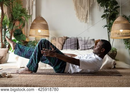 Man Practicing Yoga Indoors Doing Boat Pose Or Paripurna Navasana
