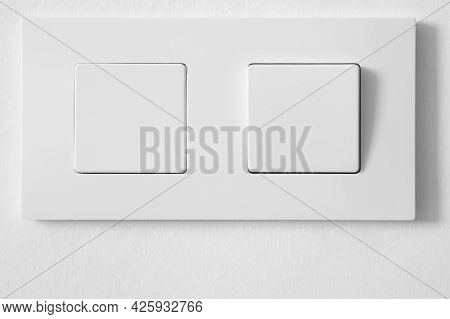 White Light Switch Over A White Textured Wall. Home Equipment