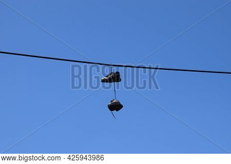 Working Shoes Hanging From A Wire In Front Of Blue Sky