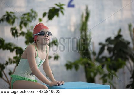 A Girl In A Swimsuit And A Swimming Cap With Glasses In The Sports Pool.