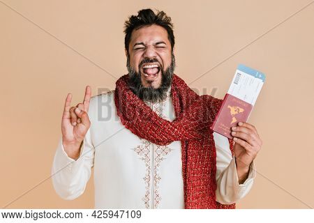 Happy Indian man in a kurta holding a passport with flight tickets