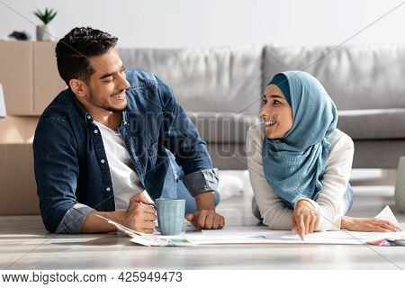 Creative Muslim Couple Laying On Floor With Apartment Scheme