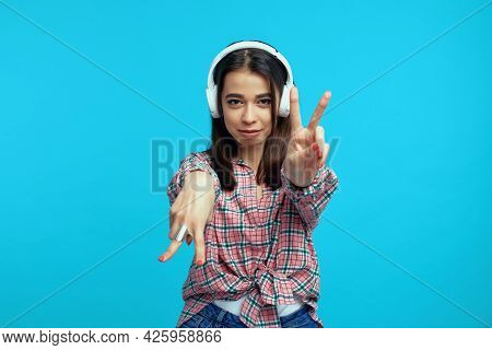 Portrait Of Happy Woman With White Headphones, Listens Music And Feels Glad, Dancing And Showing Pea