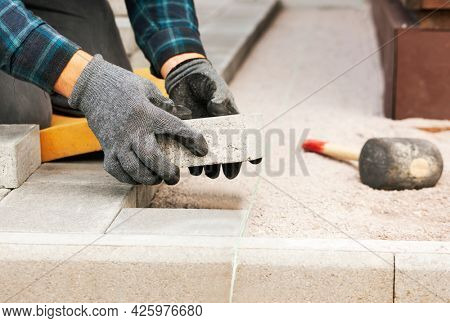 Worker lining paving slabs path