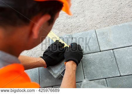 Worker lining paving slabs path