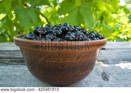 Blackcurrant Berries, Blackcurrant In A Bowl. A Plate With Berries Is On A Wooden Table. Clay Dishes