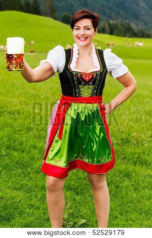 Happy young woman in a dirndl with a beer