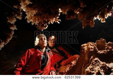 Spelunkers Admiring Stalactites In A Cave