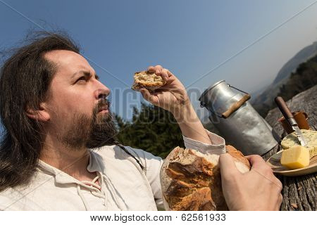 Rustically Man With Long Hair Eating Bread In The Nature