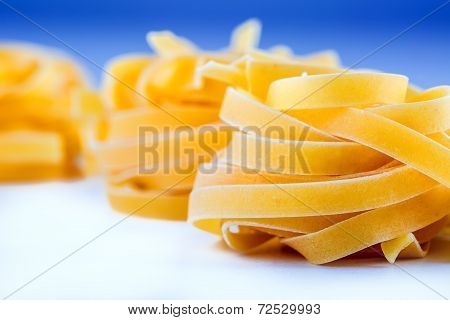 Tagliatelle pasta on white blue background.